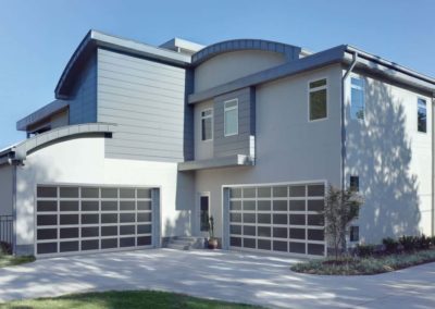 Luxurious two-story home showcasing two modern garage doors with dark framed glass panels for a sophisticated upgrade