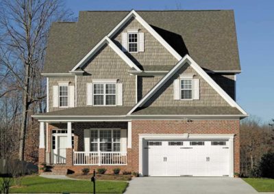 Classic white raised panel garage door with decorative windows on a traditional home, for repair or new installation services