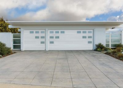 Two distinct white modern residential garage doors featuring unique, irregularly placed windows, ideal for a contemporary home design