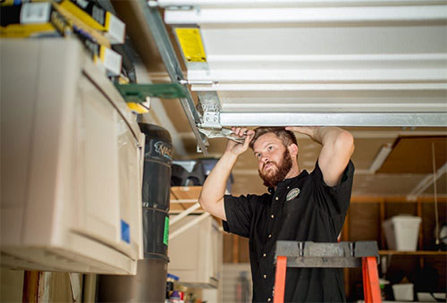 garage-door-repair-sm Repair man fixing garage door part